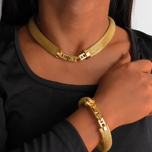 Detail of gold mesh necklace and bracelet set with H-shaped link on black top