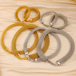 Close-up of woven mesh metal necklace and bracelet set with H-shaped clasp on satin fabric