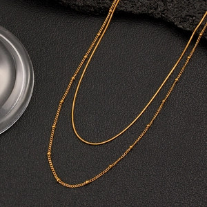 Detail einer 18K vergoldeten zweilagigen Halskette mit Schlangenkette und runden Goldperlen