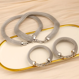 Detailed macro view of silver mesh jewelry set with H-shaped polished metal buckles