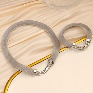 Detail of silver mesh weave necklace and bracelet set on premium silk fabric