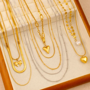 Detailaufnahme mehrlagiger Gold- und Silberhalsketten mit Herz- und Perlenanhängern