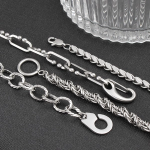Macro detail of various stainless steel chunky chains and geometric lobster clasps