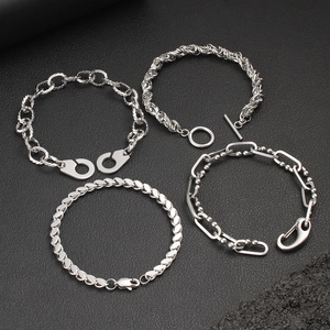 Detailed top view of four silver stainless steel bracelets on black leather texture