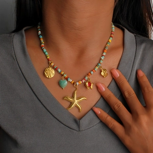 Dettaglio di collana boho con perline colorate e ciondoli a forma di stella marina su modella