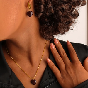Close-up of a model wearing a vintage 18K gold heart pendant necklace and matching earrings