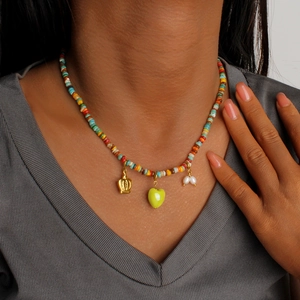 Dettaglio della collana di perline colorate con corona d'oro e ciondolo a cuore verde