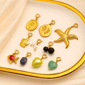 Dettaglio di ciondoli in oro 18K con stelle marine e perle su un vassoio di seta