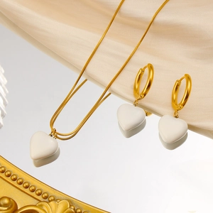French vintage heart pendant necklace and hoop earrings on elegant champagne silk fabric