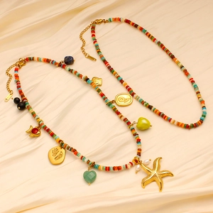 Dettaglio di ciondoli a stella marina 18K e cuore su una collana di perline stile boho