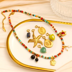 Dettaglio collana boho con ciondoli a stella marina e cuore su un vassoio dorato di lusso