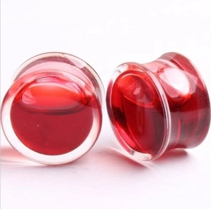 Close-up of clear ear plugs with flowing red liquid fill and smooth polished finish