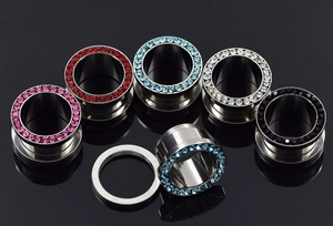 Detailed macro view of threaded stainless steel ear tunnels with multi-color rhinestones