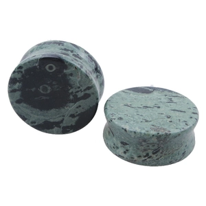 Macro view of green stone ear plugs with natural black spots and smooth curved sides