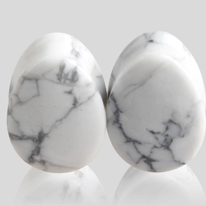 Gros plan d'écarteurs d'oreilles en pierre de howlite blanche polie en forme de goutte