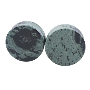 Macro shot of green stone ear plugs with natural mottled marble texture and polished finish