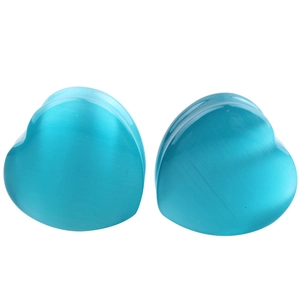 Macro detail of heart-shaped blue synthetic opal ear plugs with cat-eye effect texture