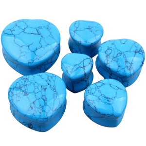 Macro detail of heart-shaped turquoise stone ear gauges in various sizes on white background
