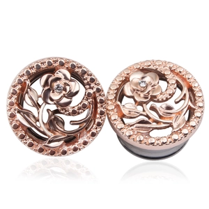 Détail d'écarteur d'oreille fleur creuse en acier or rose avec zircon central