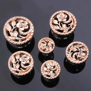 Vue macro de six écarteurs d'oreilles fleurs évidées or rose avec cristaux sur noir