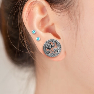 Vue macro d'un tunnel d'oreille en acier inoxydable avec motif rose ajouré