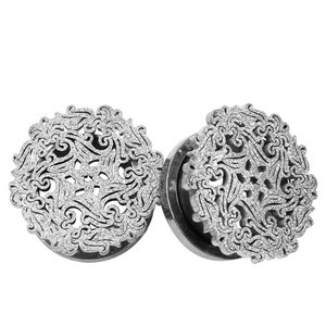 Detailed macro view of hollowed stainless steel ear plugs with intricate carved patterns