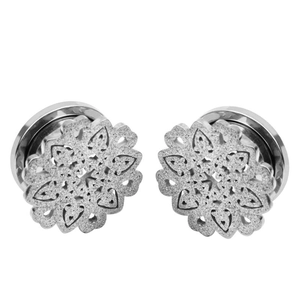 Détail de tunnels d'oreille en acier argenté avec motif floral évidé et finition pailletée