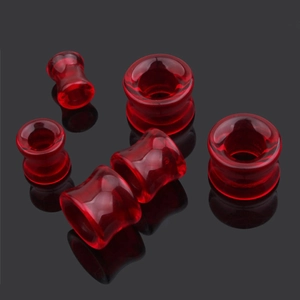 Gros plan d'écarteurs d'oreilles en verre rouge rubis sur fond noir avec reflets nets