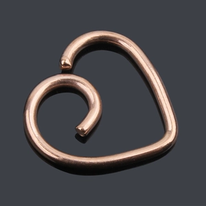 Macro detail of rose gold heart spiral piercing jewelry for cartilage or nose
