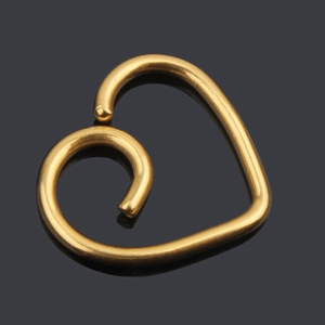 Close-up of heart-shaped gold spiral cartilage earring on a reflective black background