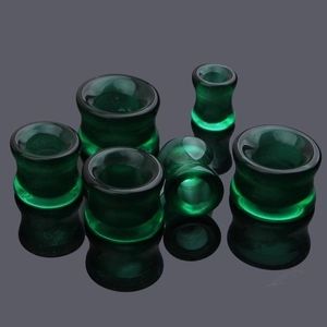 Vue macro d'écarteurs d'oreilles en verre vert foncé avec une surface polie lisse