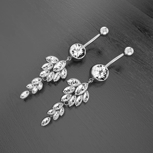 Macro view of marquise-cut zircon leaf dangle belly button rings on dark wood background