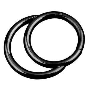Detail of two black hinged segment clicker rings for nose and ear piercings