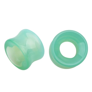 Vue macro des écarteurs d'oreilles en verre vert translucide avec design double évasé