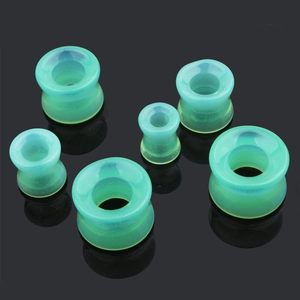 Gros plan d'écarteurs d'oreilles creux en verre vert menthe de différentes tailles
