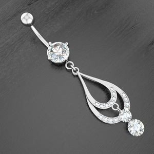 Macro view of silver belly ring with teardrop zircon pendant on black wood background
