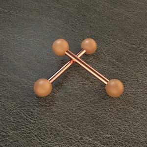 Macro shot of rose gold stainless steel piercing bars with matte finish spheres