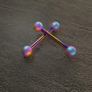Macro shot of colorful rainbow gradient barbell piercing jewelry on leather background