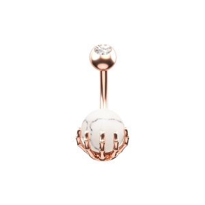 Detalle macro del piercing de ombligo mano de esqueleto oro rosa con piedra de mármol