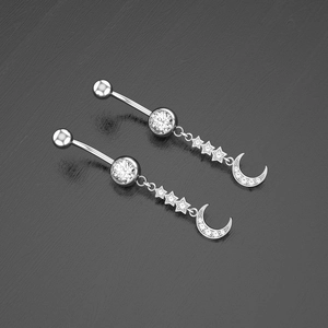 Macro shot of silver belly ring with zircon moon and stars pendants on a dark background