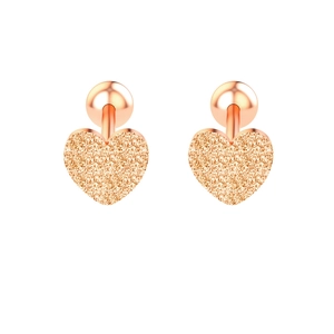 Détail des boucles d'oreilles cœur en or rose avec une texture scintillante et mate