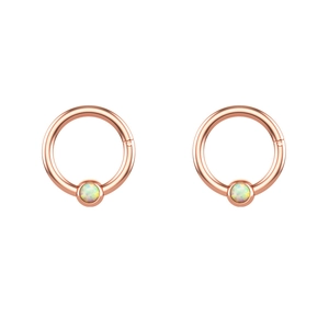 Close-up of rose gold hinged hoops with iridescent opal inlay for piercing jewelry
