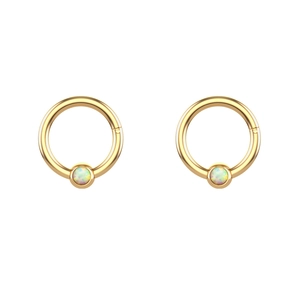 Macro view of gold stainless steel nose rings with iridescent white opal stone inlay