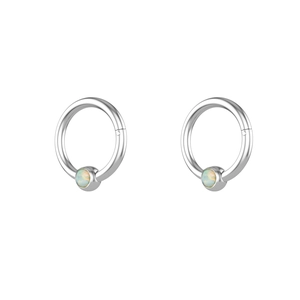 Detailed view of stainless steel piercing rings featuring blue opal stone inlays