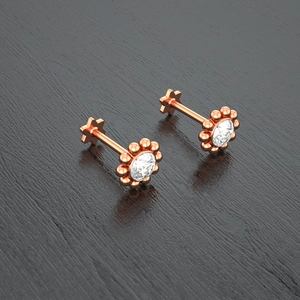 Detail shot of rose gold flower-shaped labret studs with clear center crystals