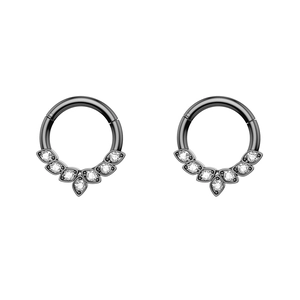 Close-up of black hinged clicker ring with seven sparkling white zircons on white background