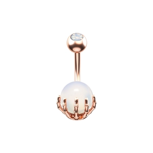 Detalle de un piercing de ombligo oro rosa con mano de esqueleto y piedra ópalo
