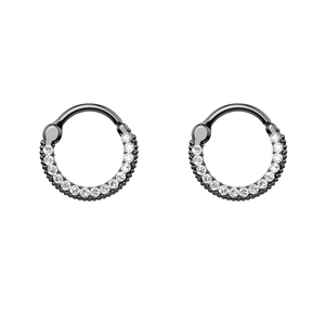 Detail of black coated circular piercing rings with sparkling white zircon stones