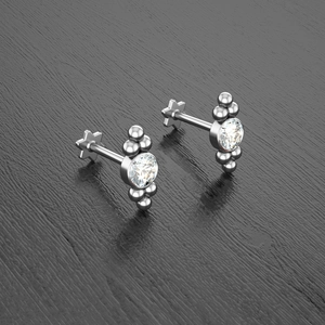 Macro shot of silver ear studs featuring crystal center and star-shaped flat back studs