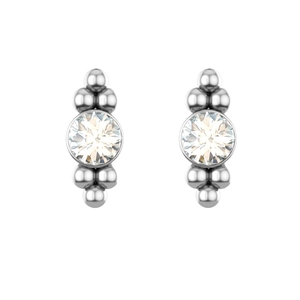 Macro detail of silver earrings with bezel-set round crystals and geometric bead accents